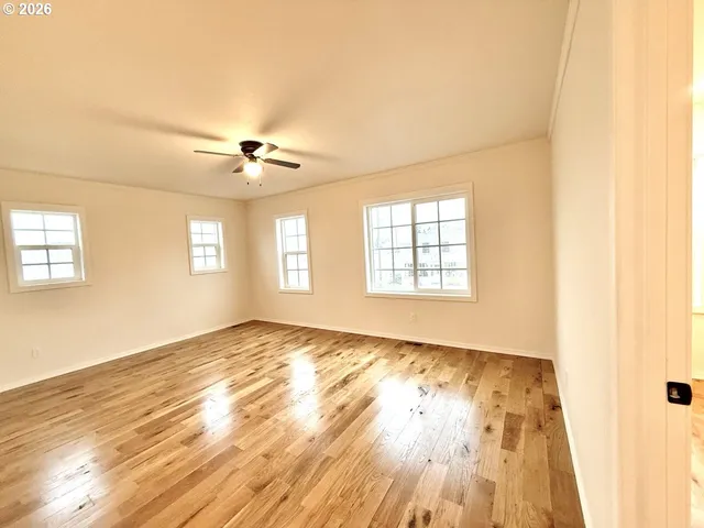 a view of an empty room with a window and wooden floor