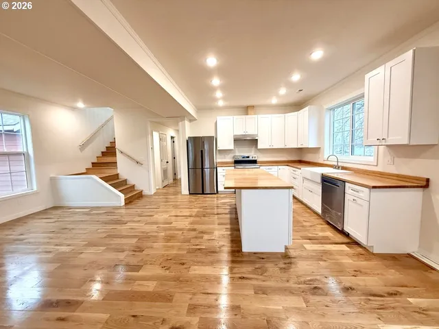 a large kitchen with kitchen island a sink a stove a center island stainless steel appliances and a window