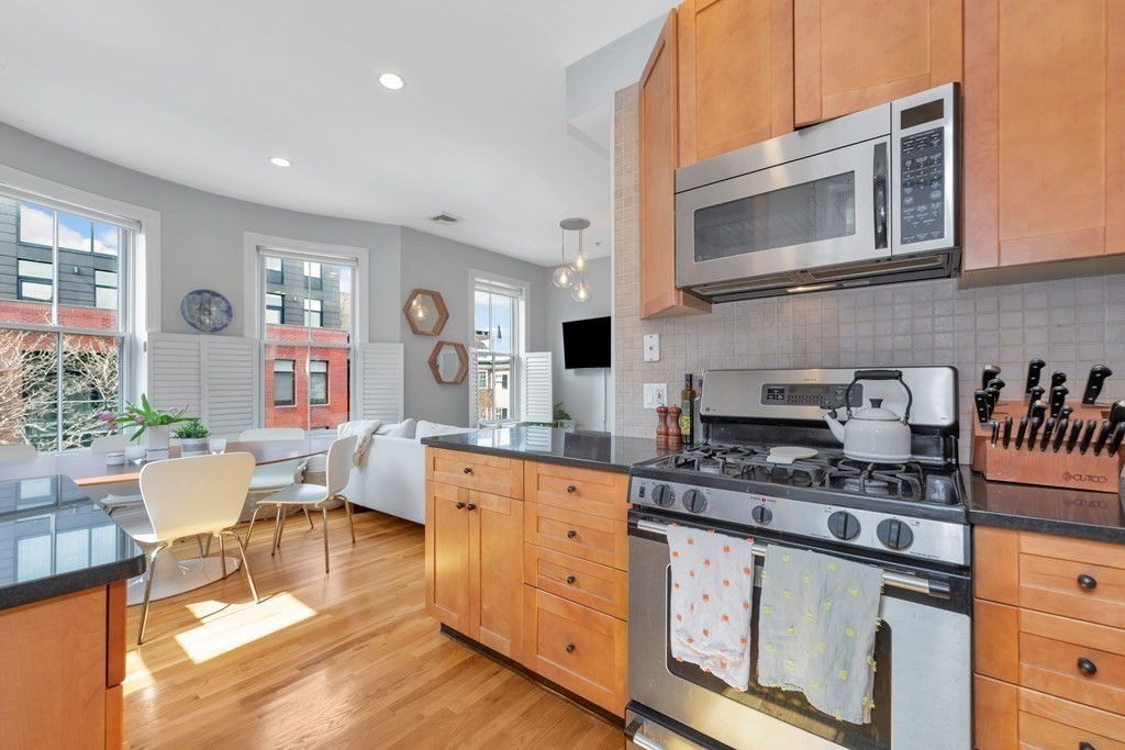 10 East Springfield Street, Unit 3 Boston, MA 02118 - Photo 13 of 26 a kitchen with stainless steel appliances granite countertop a stove a sink dishwasher and white cabinets with wooden floor