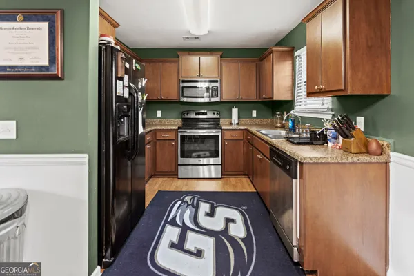 a kitchen with stainless steel appliances granite countertop a stove top oven a sink and dishwasher a refrigerator with wooden floor