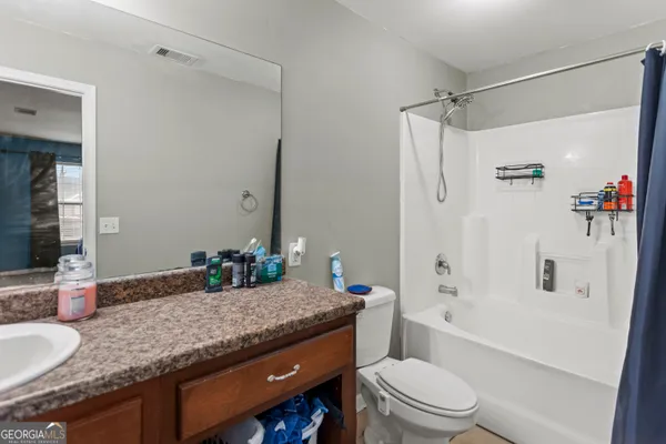 a bathroom with a granite countertop sink mirror vanity and toilet