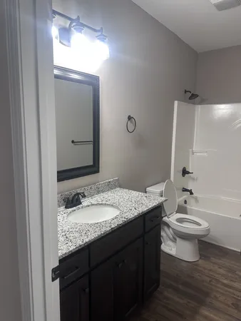 a bathroom with a granite countertop sink toilet and mirror