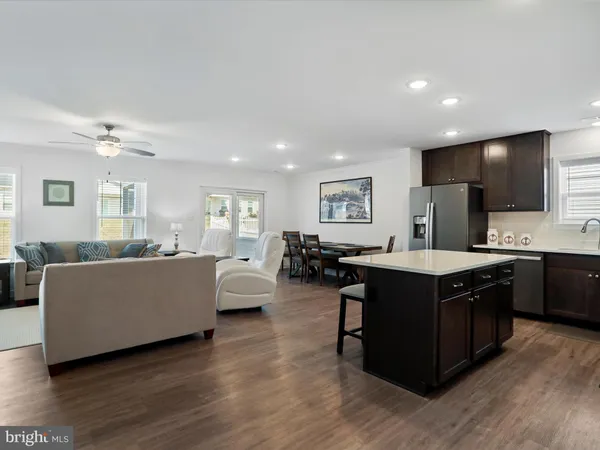 a living room with couches and kitchen view with wooden floor