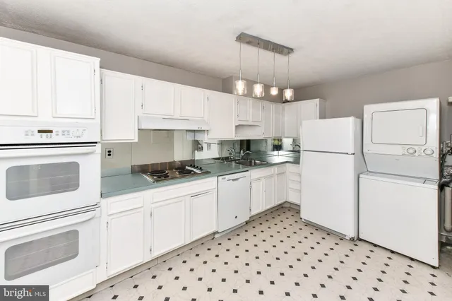 a kitchen with granite countertop a sink a stove top oven and cabinets