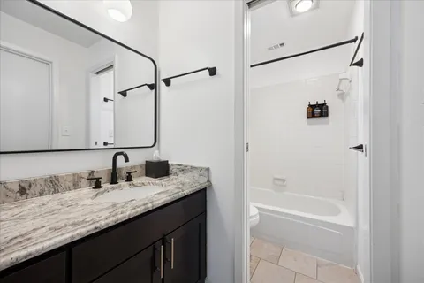 a bathroom with a granite countertop sink a mirror and a bathtub