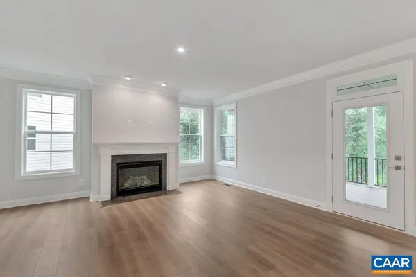 an empty room with wooden floor fireplace and windows