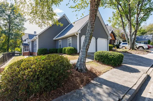 a view of a house with a yard and large trees