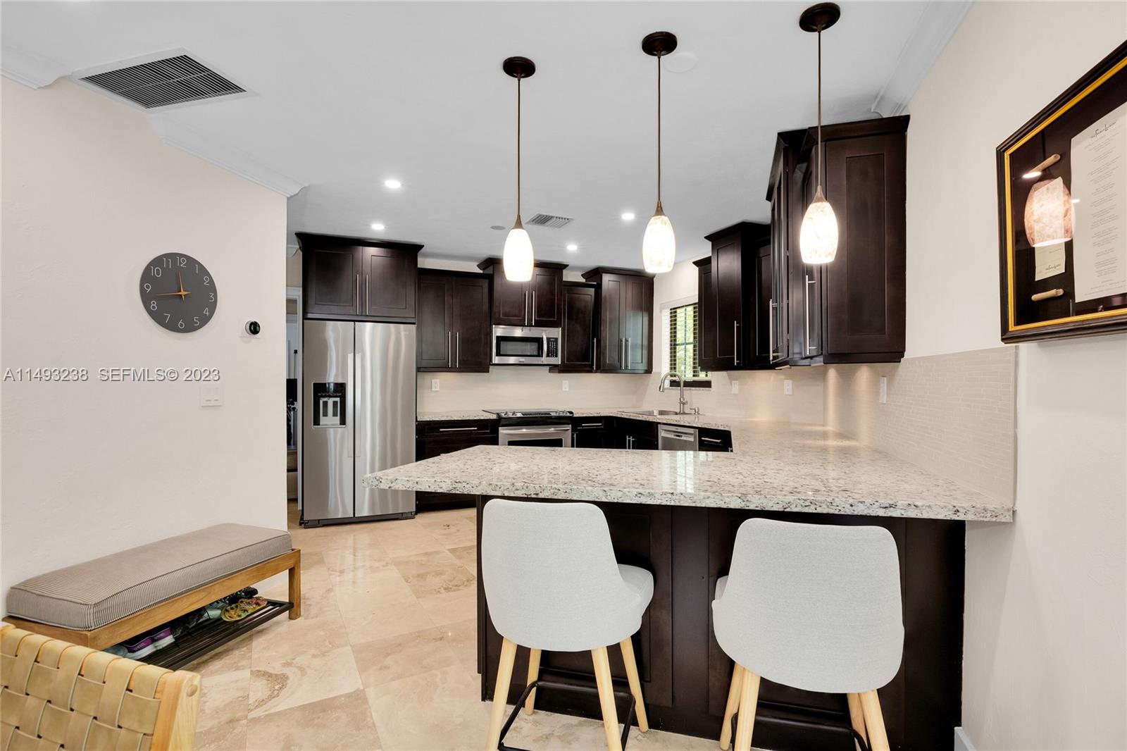 605 Blue Road Coral Gables, FL 33146 - Photo 15 of 34 a kitchen with stainless steel appliances granite countertop a sink a stove a refrigerator a dining table and chairs