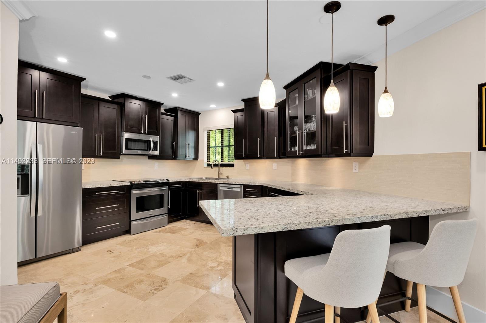 605 Blue Road Coral Gables, FL 33146 - Photo 16 of 34 a kitchen with granite countertop a table chairs stove and refrigerator