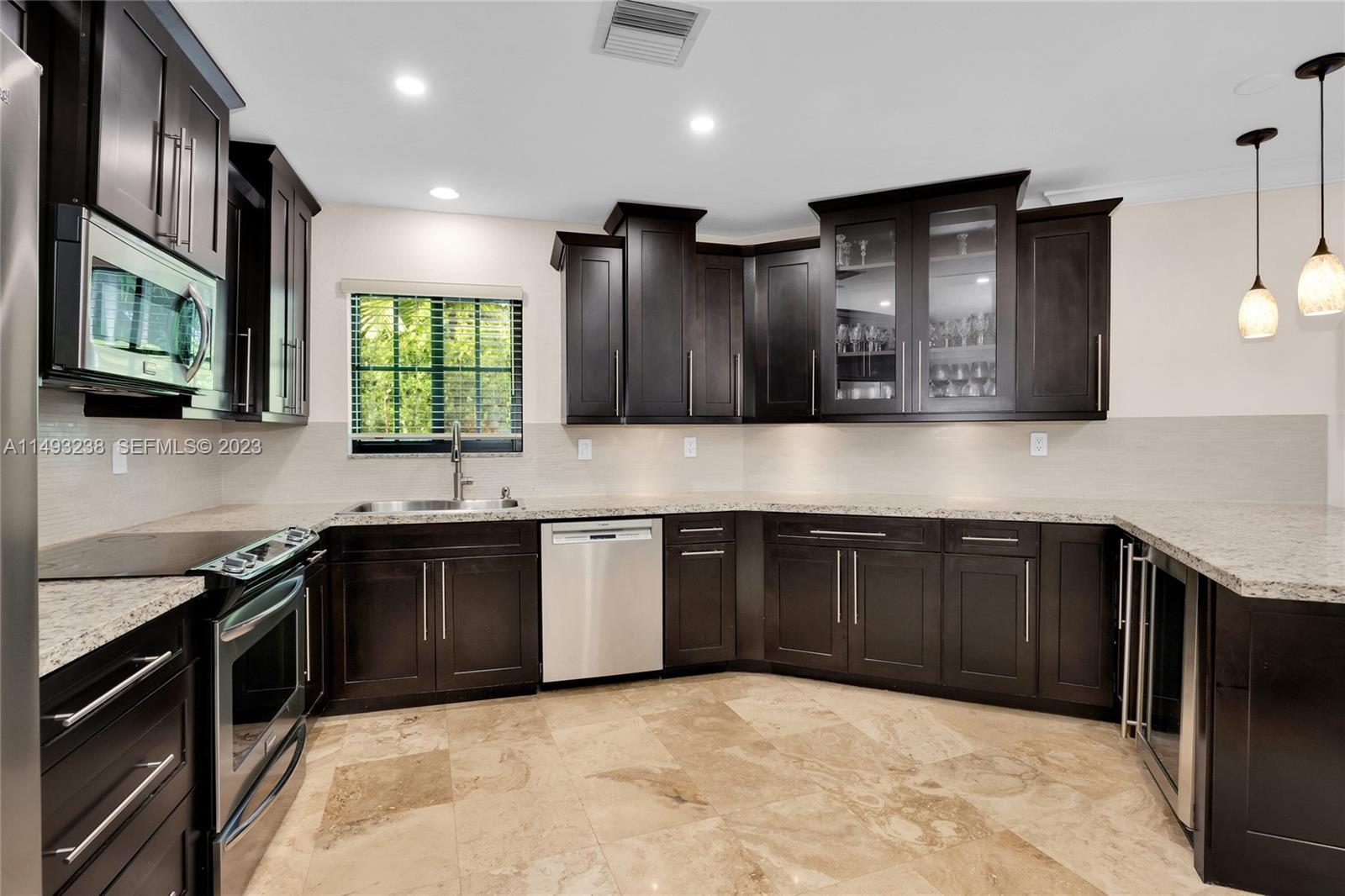 605 Blue Road Coral Gables, FL 33146 - Photo 17 of 34 a kitchen with stainless steel appliances granite countertop wooden cabinets a stove top oven a sink and dishwasher