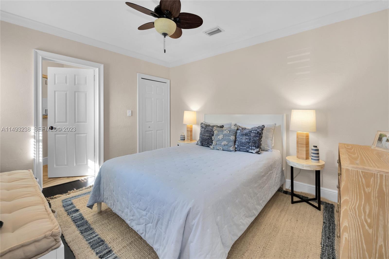 605 Blue Road Coral Gables, FL 33146 - Photo 23 of 34 a spacious bedroom with a bed and a chandelier