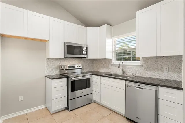a kitchen with granite countertop white cabinets sink and stainless steel appliances