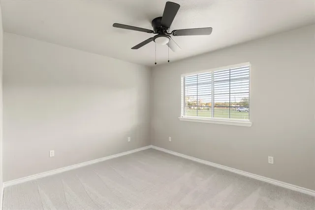 an empty room with a window and a ceiling fan