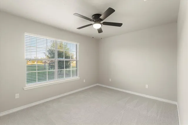 an empty room with window and ceiling fan