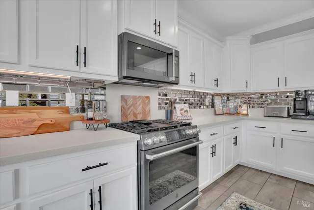 a kitchen with stainless steel appliances granite countertop a stove a sink and a microwave