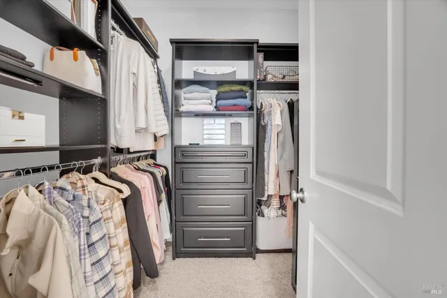 a view of walk in closet with clothes and shoes