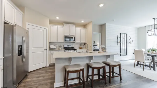 a kitchen with stainless steel appliances a dining table chairs refrigerator and cabinets