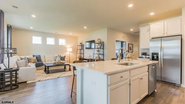 a large kitchen with kitchen island a refrigerator a sink dishwasher a dining table and chairs with wooden floor