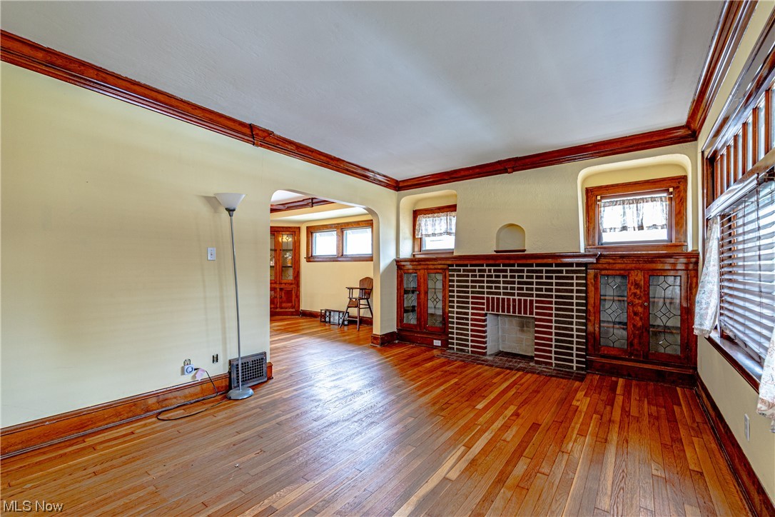 3337 Ralph Avenue Cleveland, OH 44109 - Photo 5 of 30 Unfurnished living room featuring a brick fireplace, ceiling fan, ornamental molding, and hardwood / wood-style floors