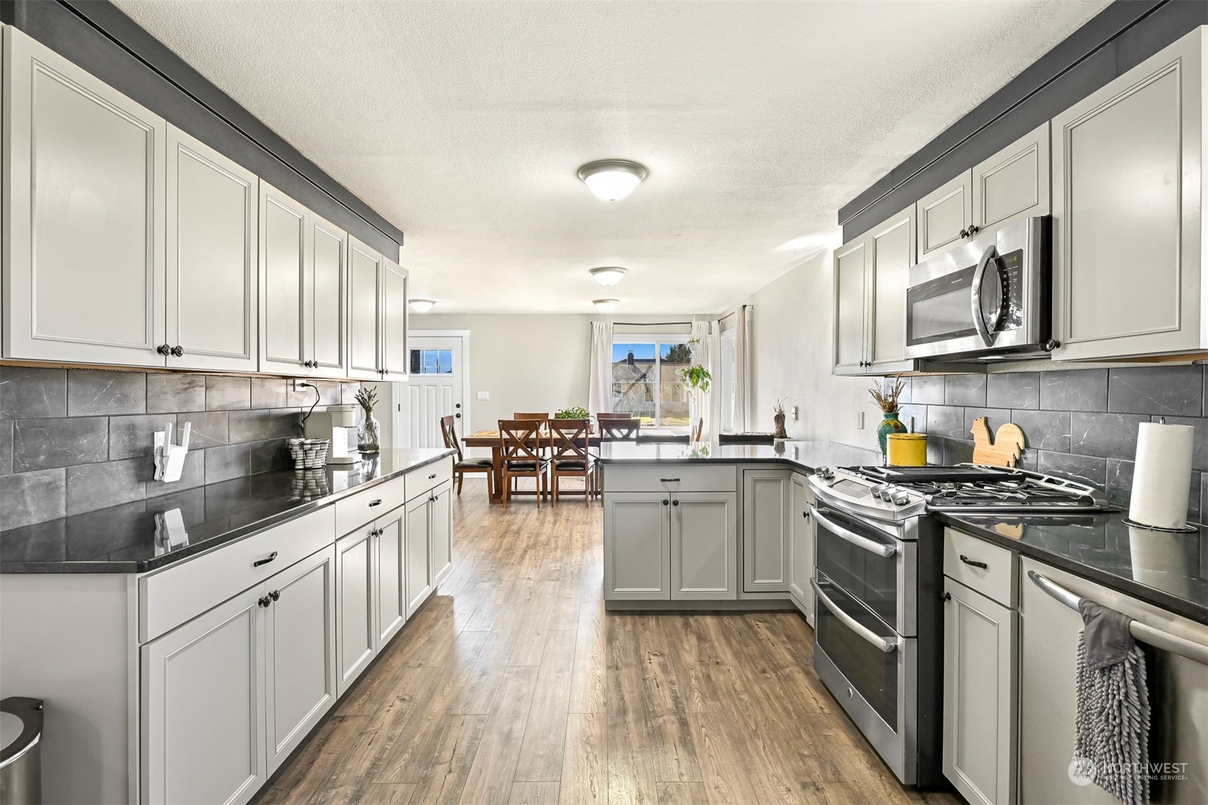 244 Front Street Sumas, WA 98295 - Photo 20 of 40 a kitchen with stainless steel appliances granite countertop a stove top oven a sink dishwasher and white cabinets with wooden floor