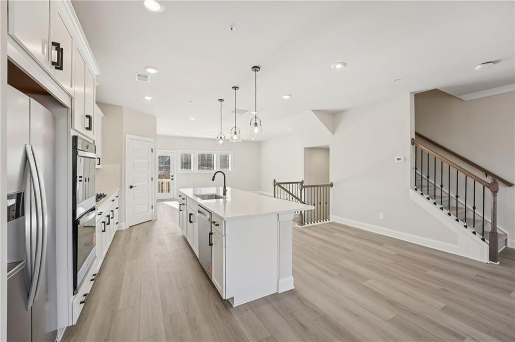 6440 Pinin Place Cumming, GA 30041 - Photo 27 of 52 a large white kitchen with wooden floor and stainless steel appliances
