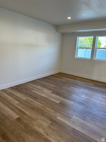 1886 North 300 West Logan, UT 84341 - Photo 8 of 18 Spacious room featuring wood-finish flooring, white baseboards, recessed ceiling lighting, and two casement windows with white frames