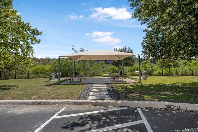 a view of a street with a big yard and large trees