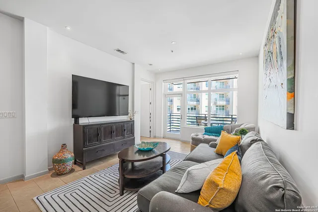 a living room with furniture a flat screen tv and a window