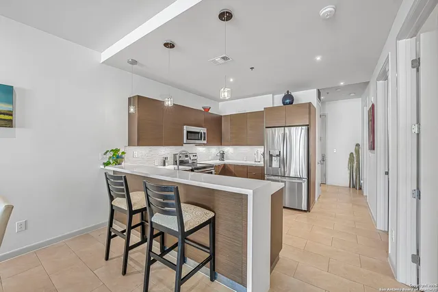 a kitchen with stainless steel appliances a dining table chairs and a refrigerator