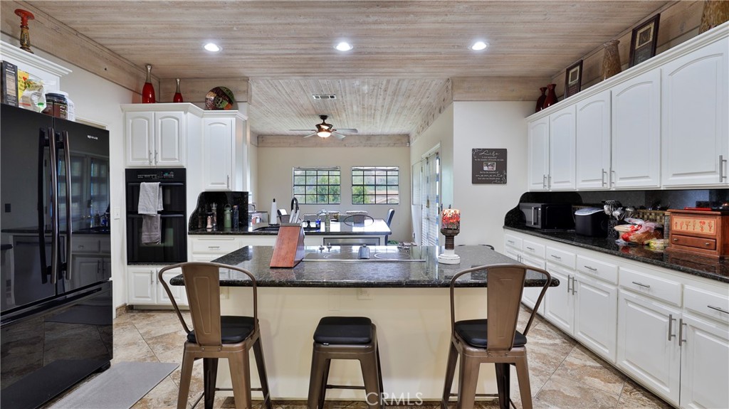 12698 La Solana Drive Redlands, CA 92373 - Photo 13 of 65 a kitchen with stainless steel appliances kitchen island granite countertop a table chairs sink and cabinets