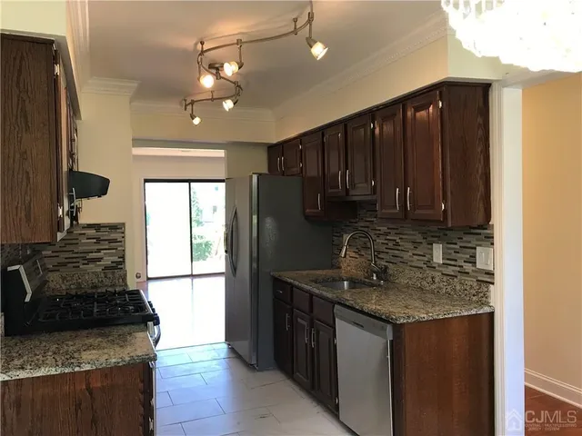a kitchen with granite countertop stainless steel appliances a sink stove and cabinets