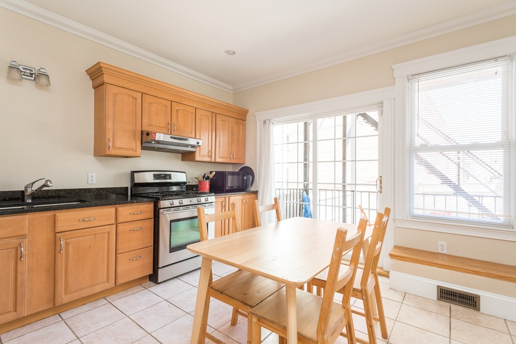 23 Hurd Road, Unit 1 Brookline, MA 02445 - Photo 5 of 12 a kitchen with stainless steel appliances granite countertop a stove a sink a dining table and chairs