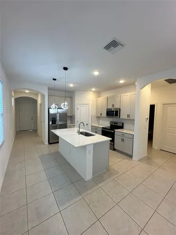 a large white kitchen with a large window and stainless steel appliances