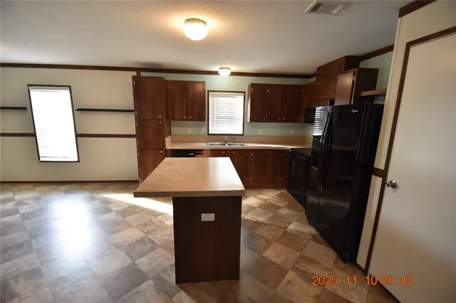 a kitchen with stainless steel appliances a refrigerator a stove a sink cabinets and a dining table