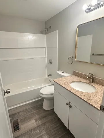 a bathroom with a granite countertop toilet sink and mirror
