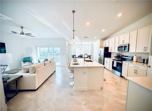 a large white kitchen with kitchen island a stove a cabinets a chimney a sink and a window