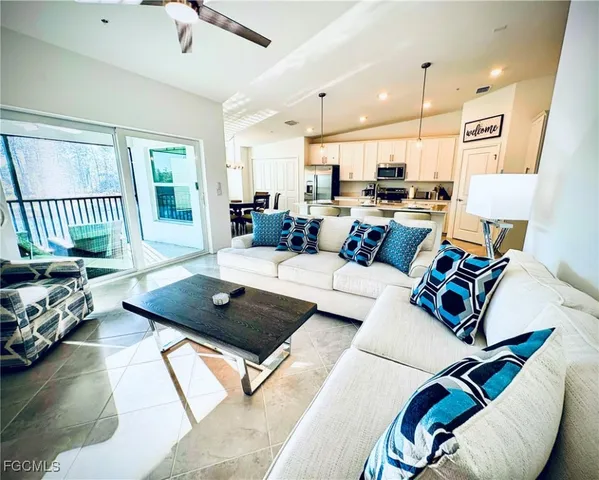 a living room with furniture kitchen view and a window