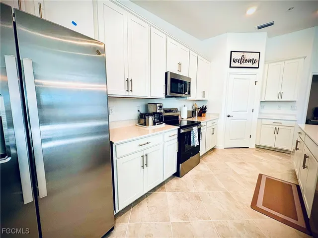 a kitchen with granite countertop a refrigerator sink and white cabinets