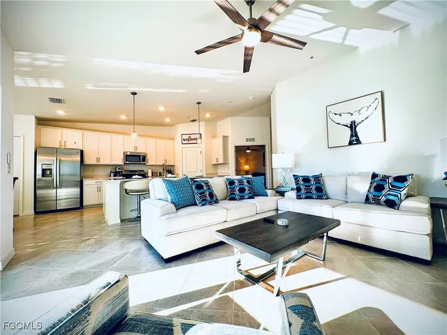 a living room with furniture kitchen view and a chandelier