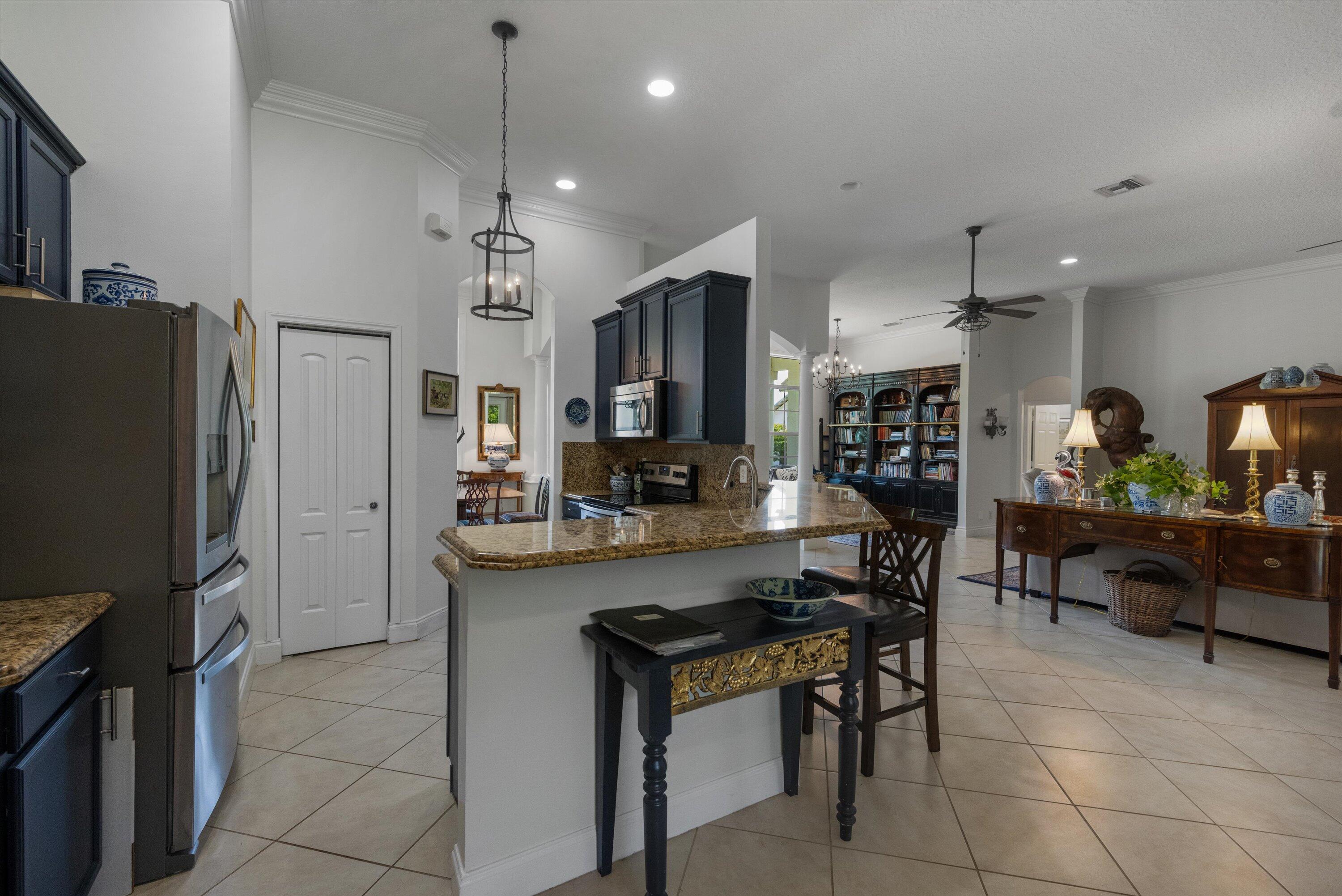 19986 Black Falcon Road Loxahatchee, FL 33470 - Photo 23 of 105 a kitchen with stainless steel appliances kitchen island granite countertop a refrigerator and a stove top oven