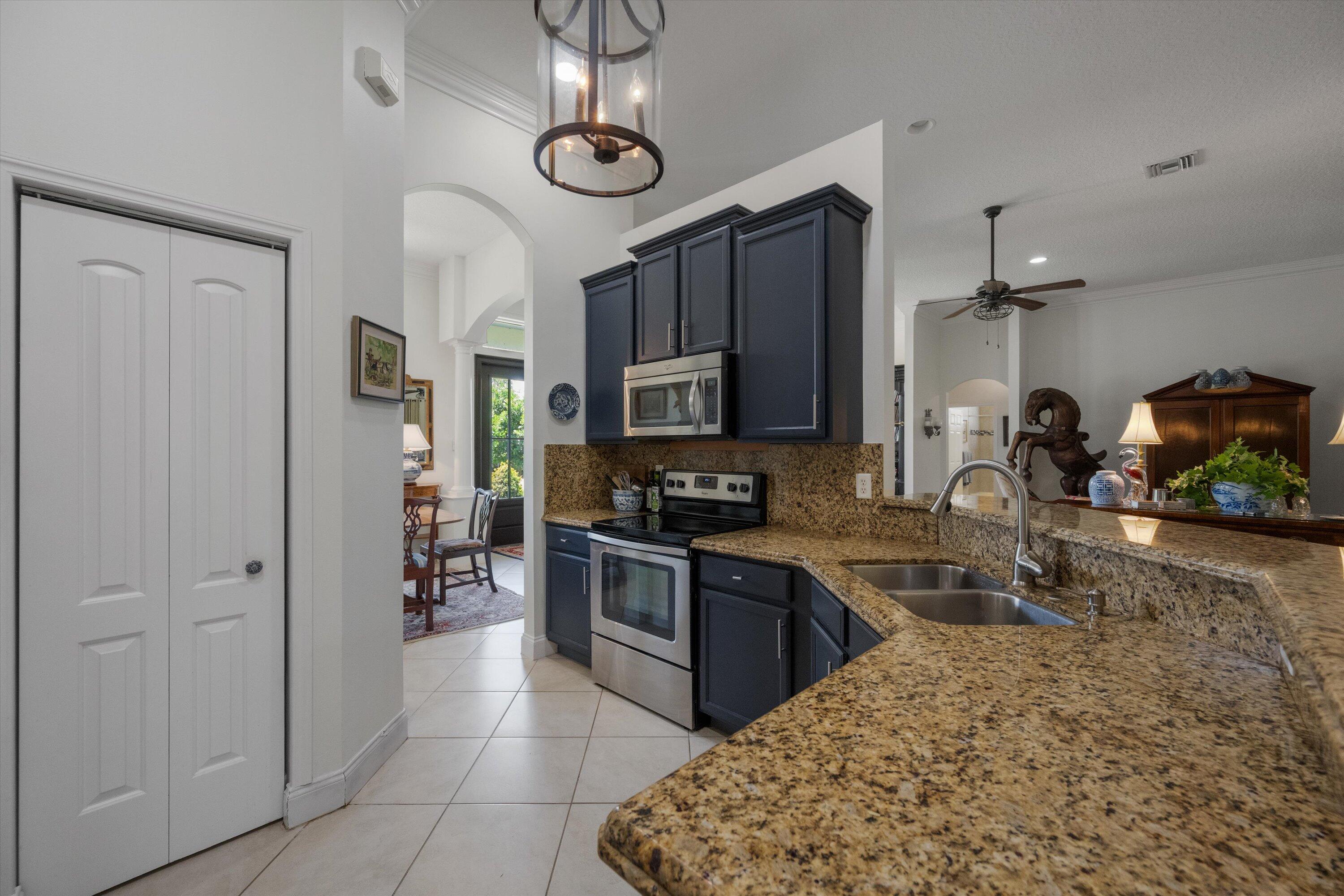 19986 Black Falcon Road Loxahatchee, FL 33470 - Photo 24 of 105 a kitchen with stainless steel appliances granite countertop a sink and a refrigerator