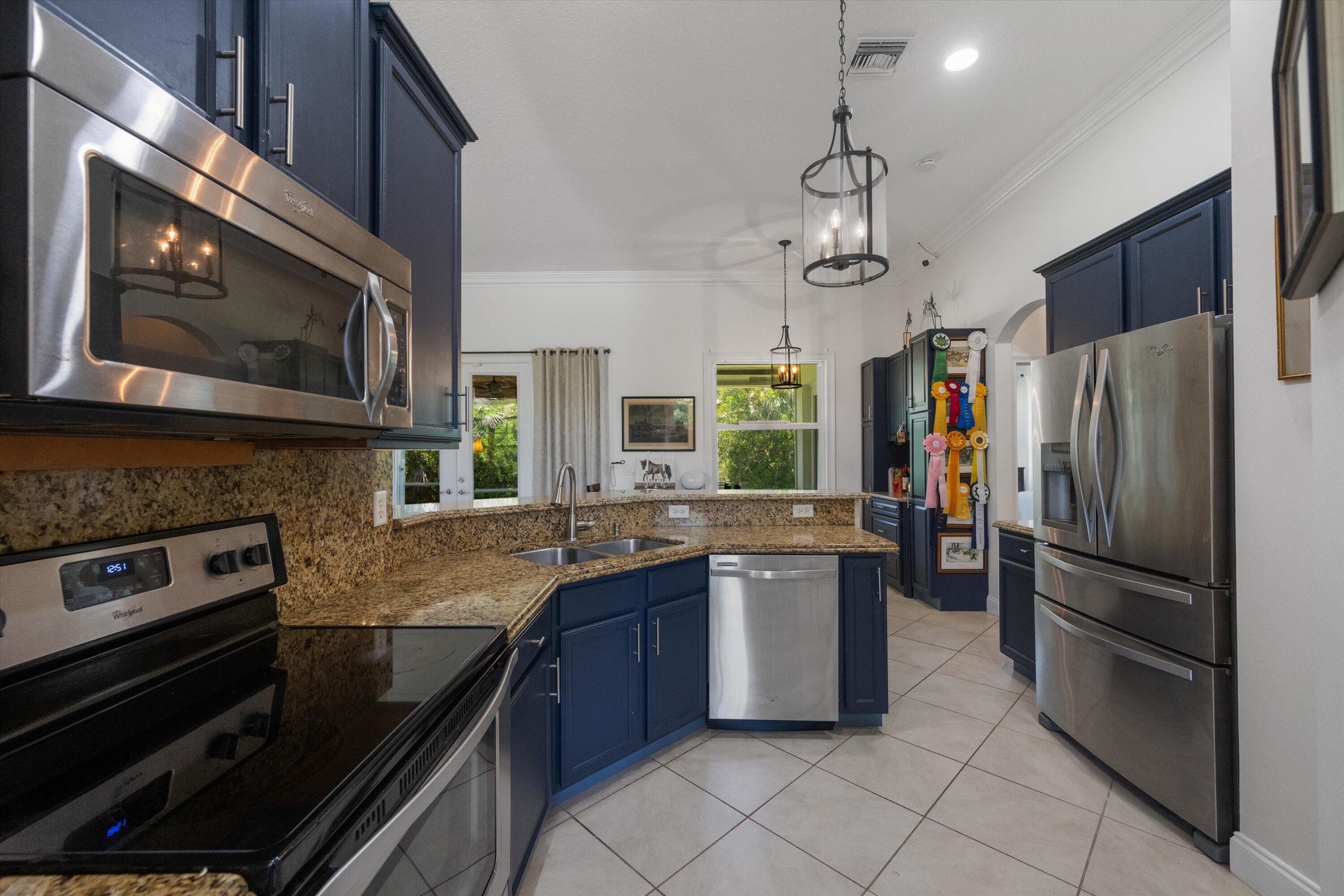 19986 Black Falcon Road Loxahatchee, FL 33470 - Photo 26 of 105 a kitchen with granite countertop stainless steel appliances and wooden cabinets