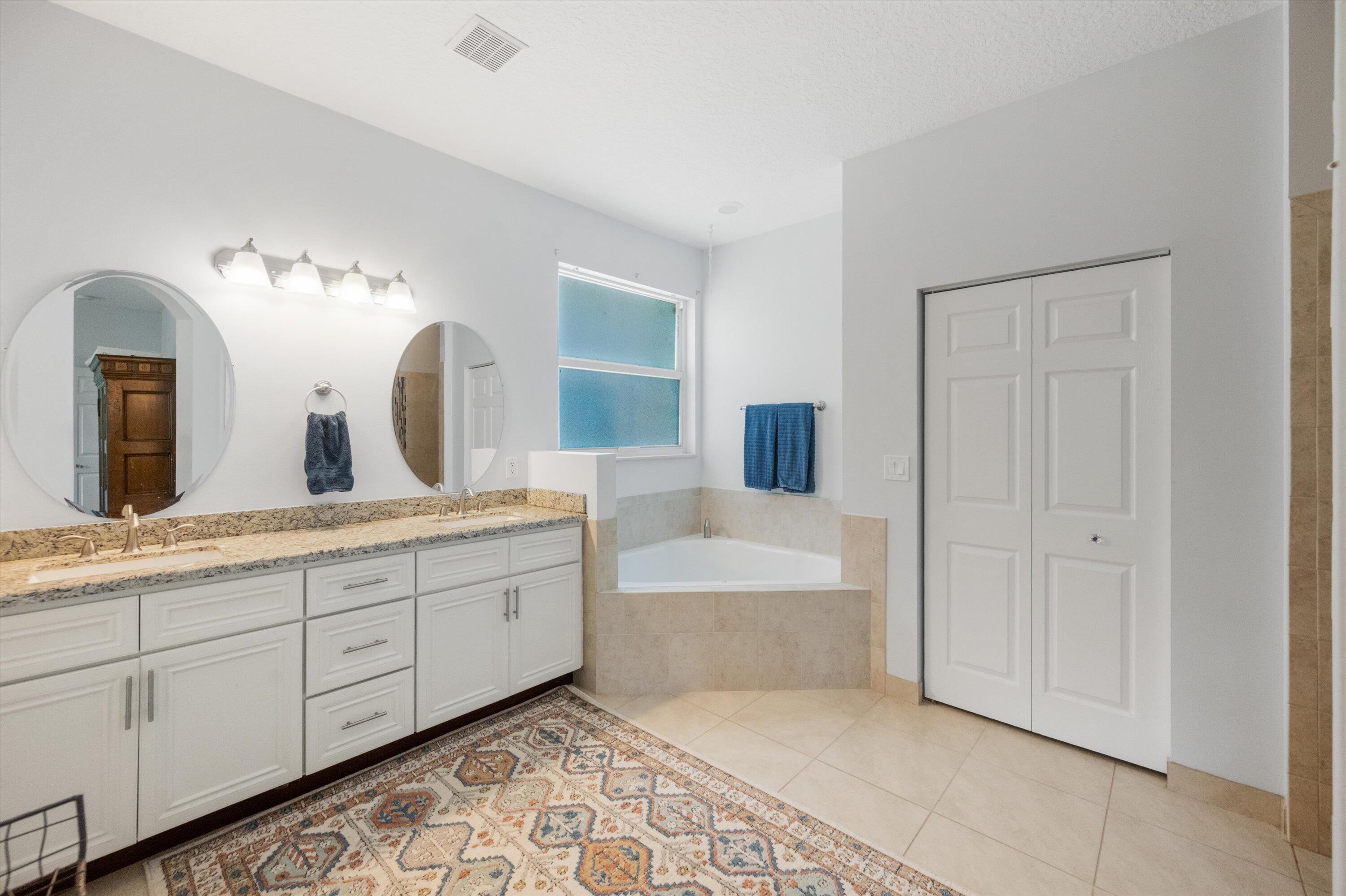 19986 Black Falcon Road Loxahatchee, FL 33470 - Photo 44 of 105 a spacious bathroom with a double vanity sink and a mirror