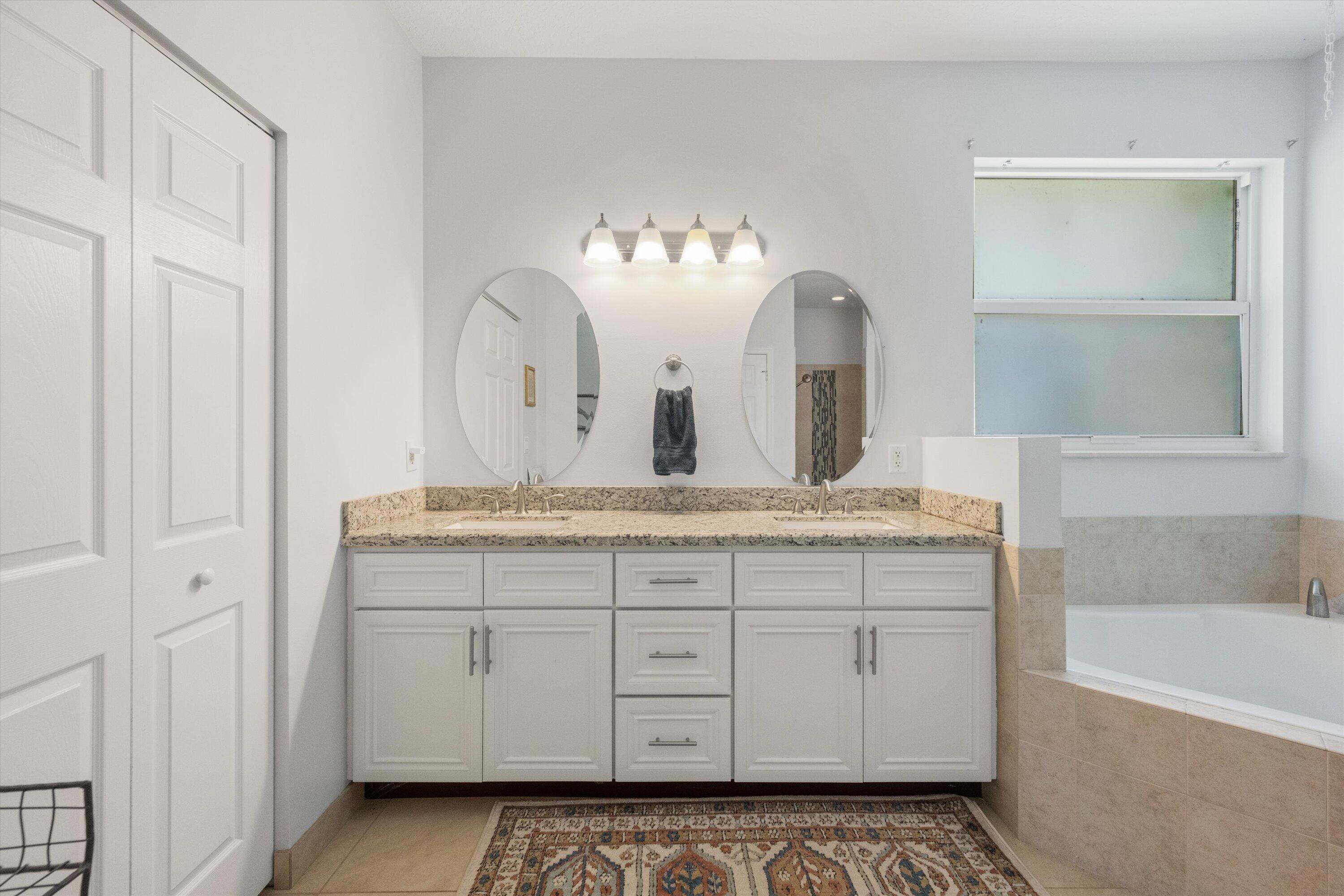 19986 Black Falcon Road Loxahatchee, FL 33470 - Photo 45 of 105 a bathroom with a granite countertop sink a mirror and a bathtub