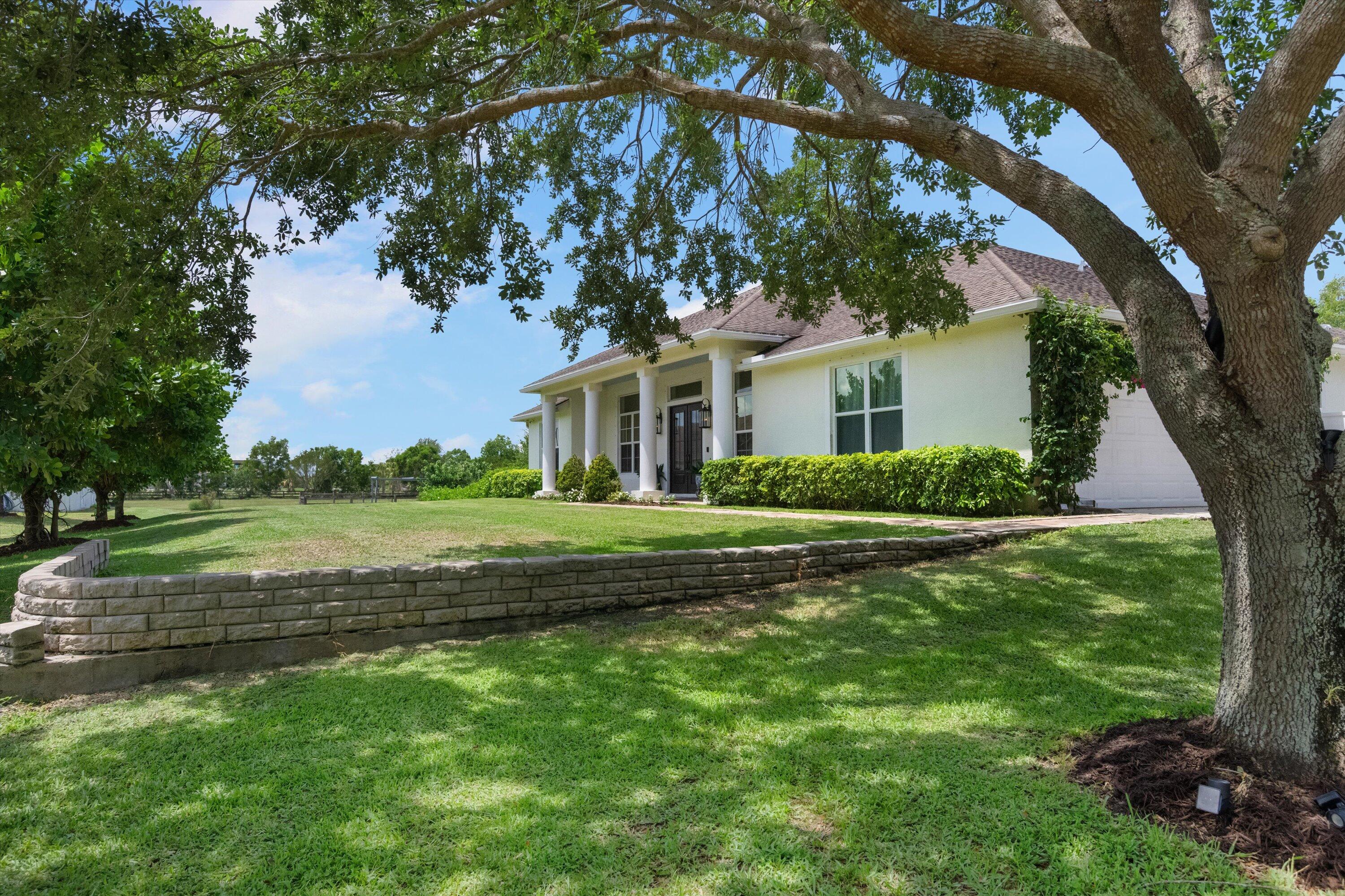 19986 Black Falcon Road Loxahatchee, FL 33470 - Photo 8 of 105 a front view of a house with a garden
