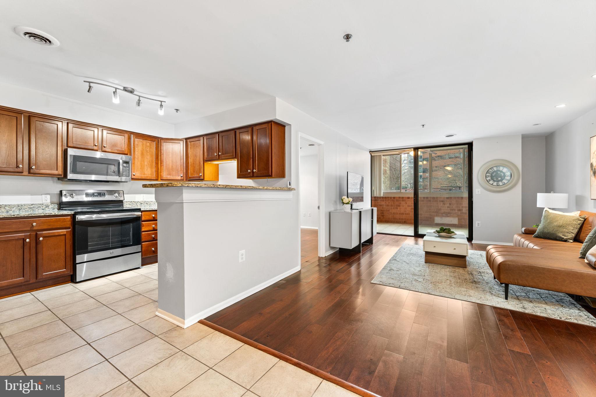 1001 North Vermont Street, Unit 103 Arlington, VA 22201 - Photo 2 of 20 a kitchen with granite countertop a stove top oven a sink dishwasher a dining table and chairs with wooden floor