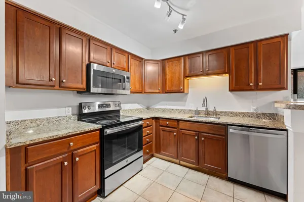 a kitchen with granite countertop wooden cabinets stainless steel appliances and a counter space
