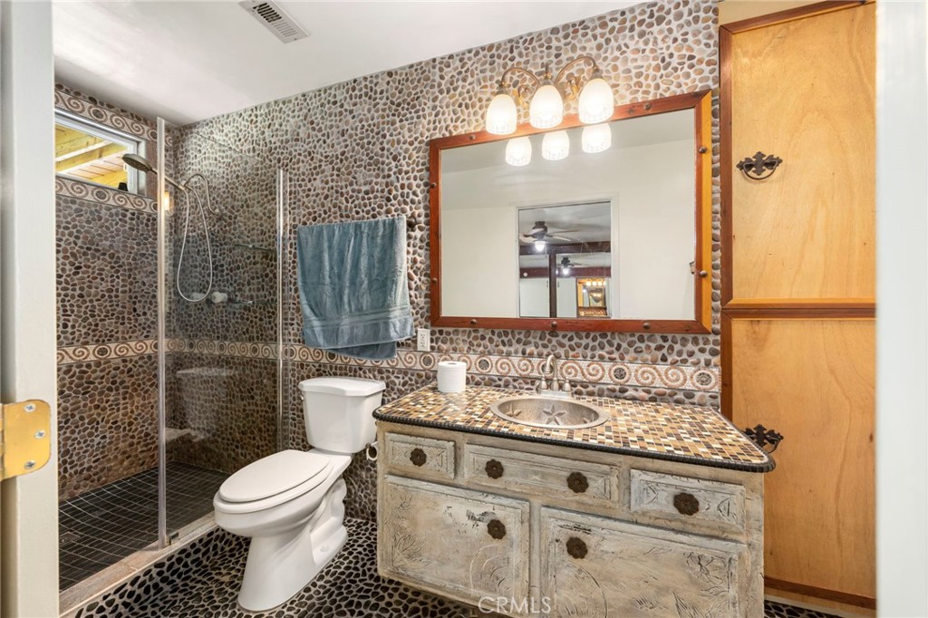 2883 Soledad Canyon Road Acton, CA 93510 - Photo 59 of 64 a bathroom with a granite countertop toilet a sink and a mirror