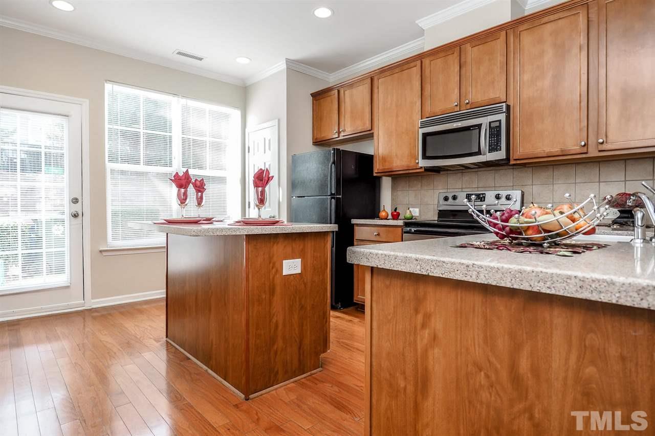 2965 Casona Way Raleigh, NC 27616 - Photo 13 of 25 a kitchen with stainless steel appliances granite countertop a stove top oven a sink dishwasher and a microwave with wooden floor
