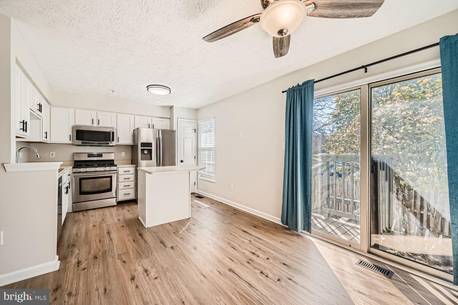 8540 Pine Meadows Drive Odenton, MD 21113 - Photo 6 of 29 a kitchen with stainless steel appliances a stove top oven a refrigerator a sink and dishwasher with wooden floor